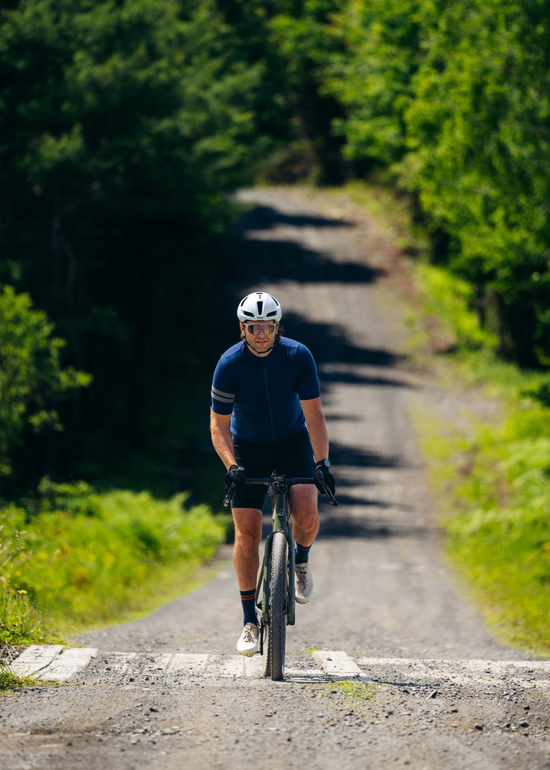 Person cycling on a dirt road surrounded by trees