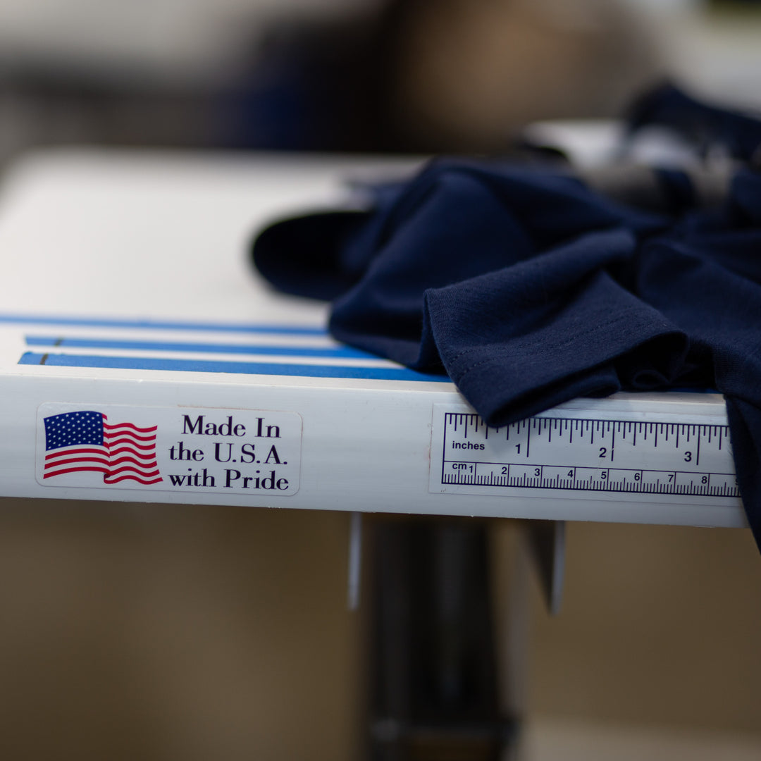 The edge of a sewing work bench showing a sticker that says Made in the USA with Pride, with Pinebury Merino Wool on the top in Atlantic Blue
