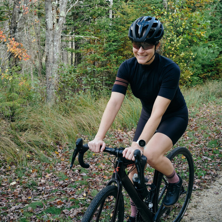 Pinebury Grafton Short Sleeve Merino Wool Cycling Jersey in Black, Woman gravel cycling in Maine in all black smiling
