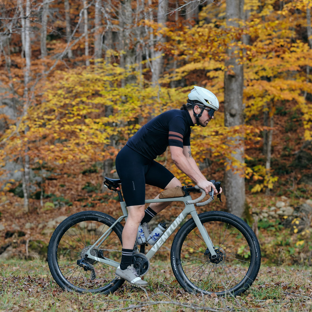 Pinebury Grafton Short Sleeve Merino Wool Cycling Jersey in Black, Side view of man riding gravel bike in the fall in Maine