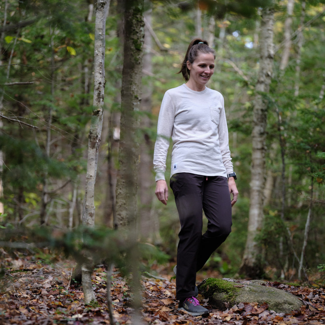 Pinebury Greenwood Long Sleeve Performance Tee in Moonbeam, Woman walking in the woods smiling in Maine