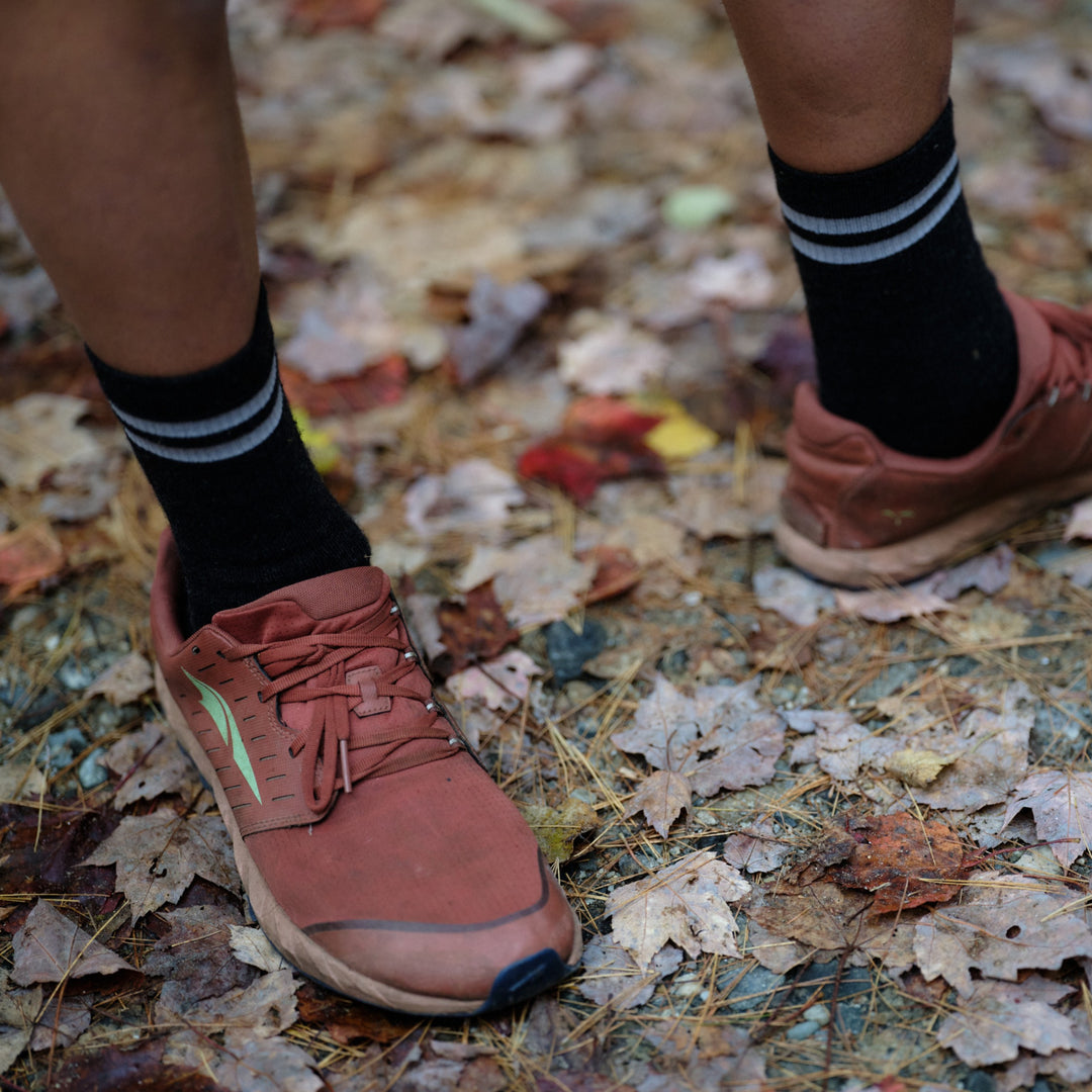 Pinebury Mountain Merino Wool Sock in Charcoal, Person wearing running shoes with black socks standing on fallen leaves