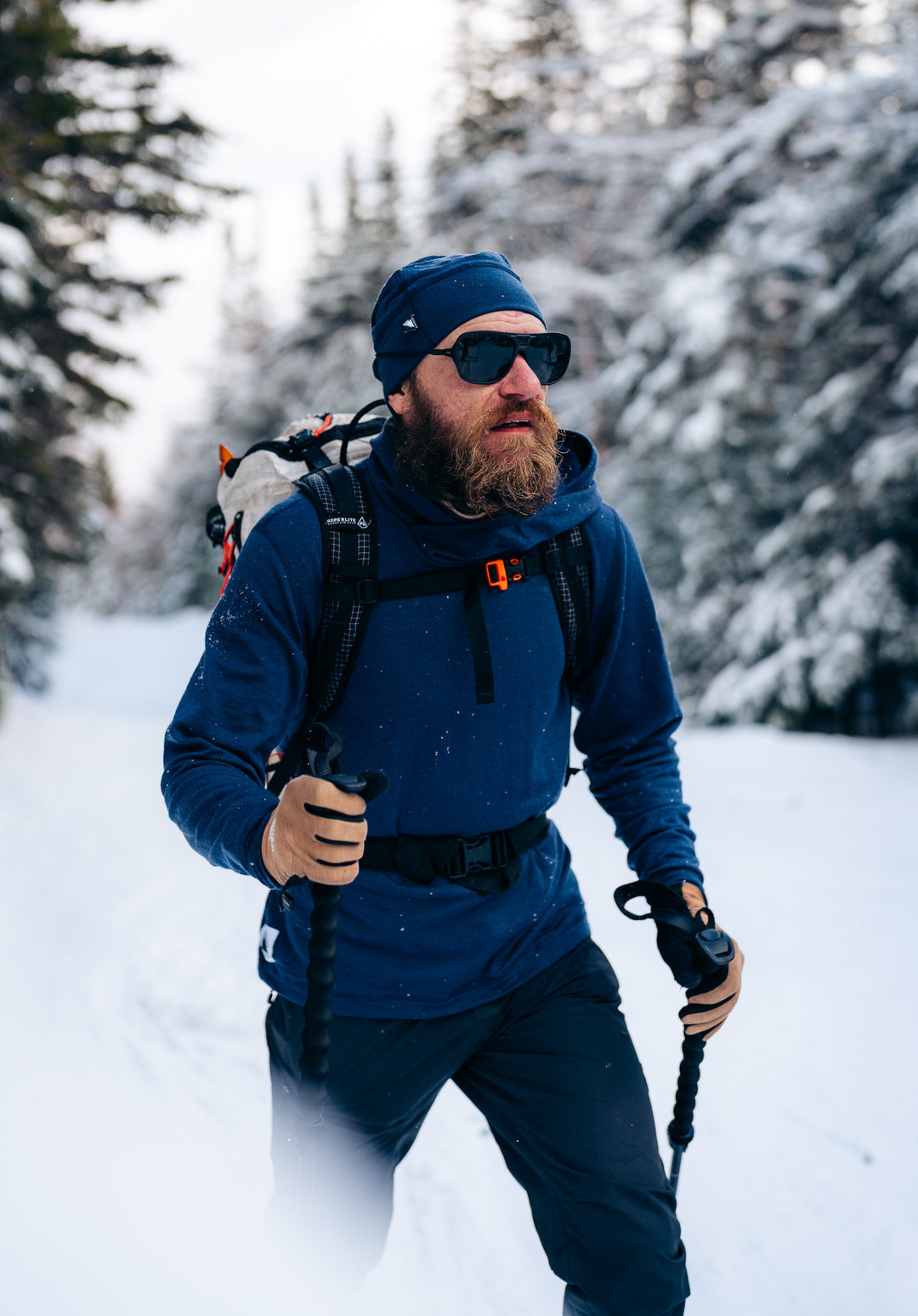 Person hiking in a snowy forest wearing winter gear