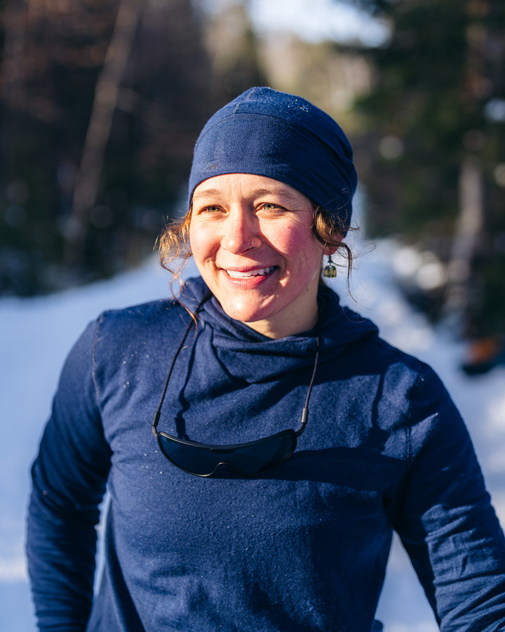 Person wearing a blue outfit and hat standing in a snowy landscape