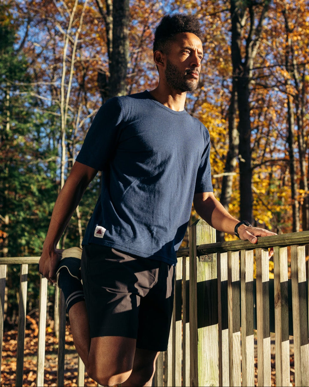 Man stretching on a wooden deck with autumn trees in the background