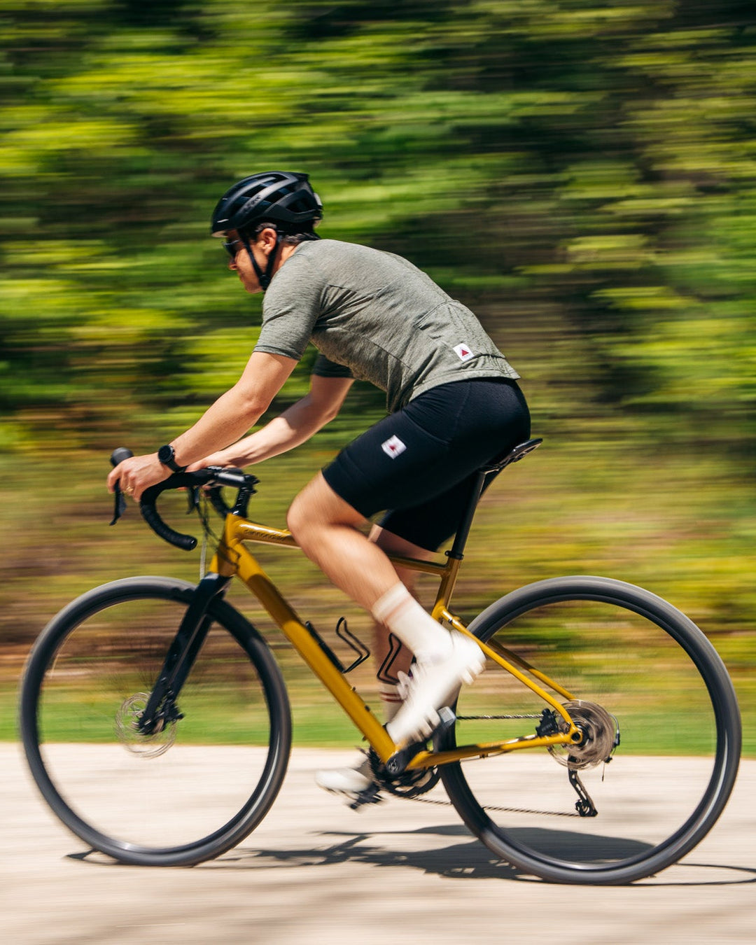Person riding a yellow bicycle on a road with greenery in the background