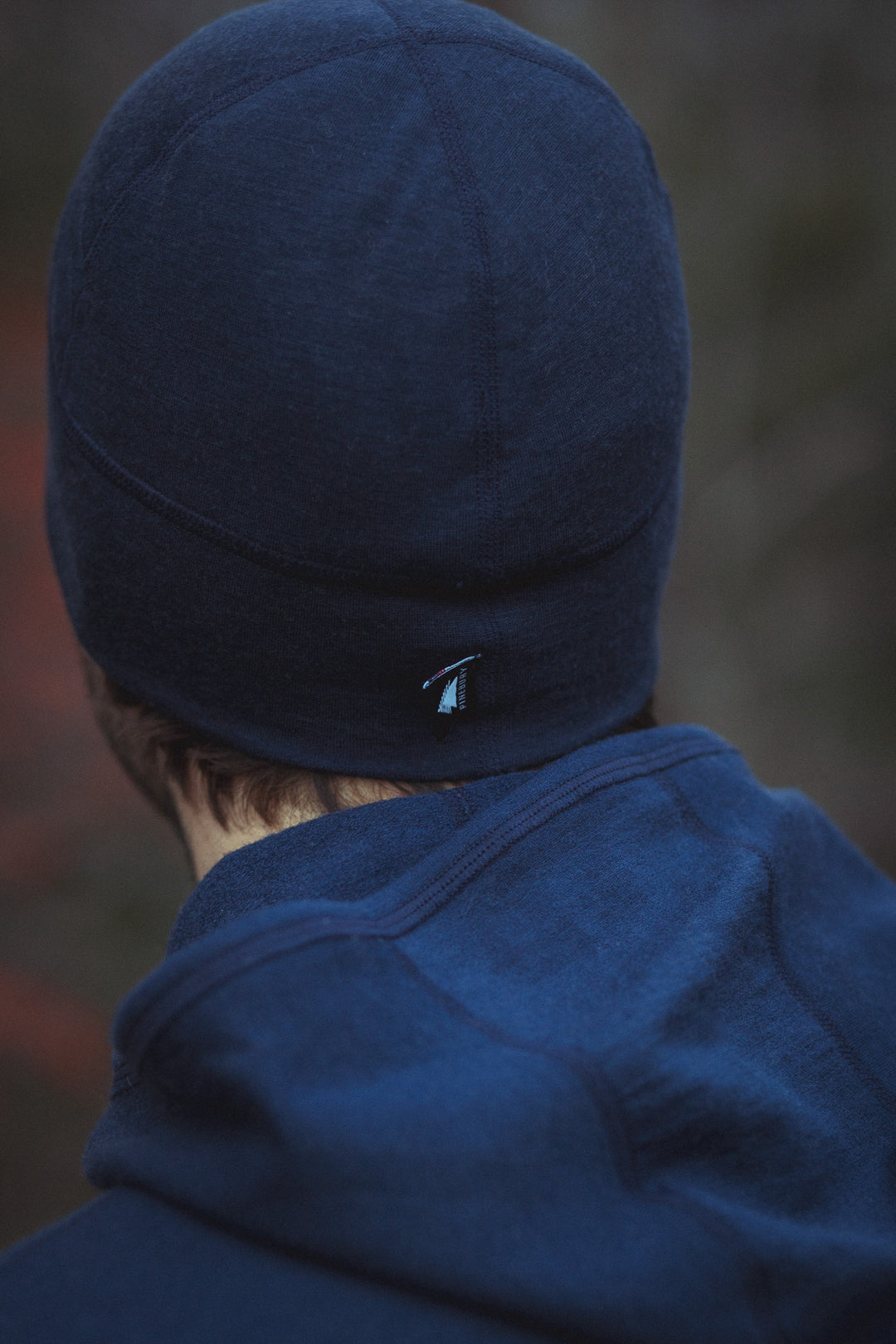 Person wearing a blue beanie and jacket with a blurred background