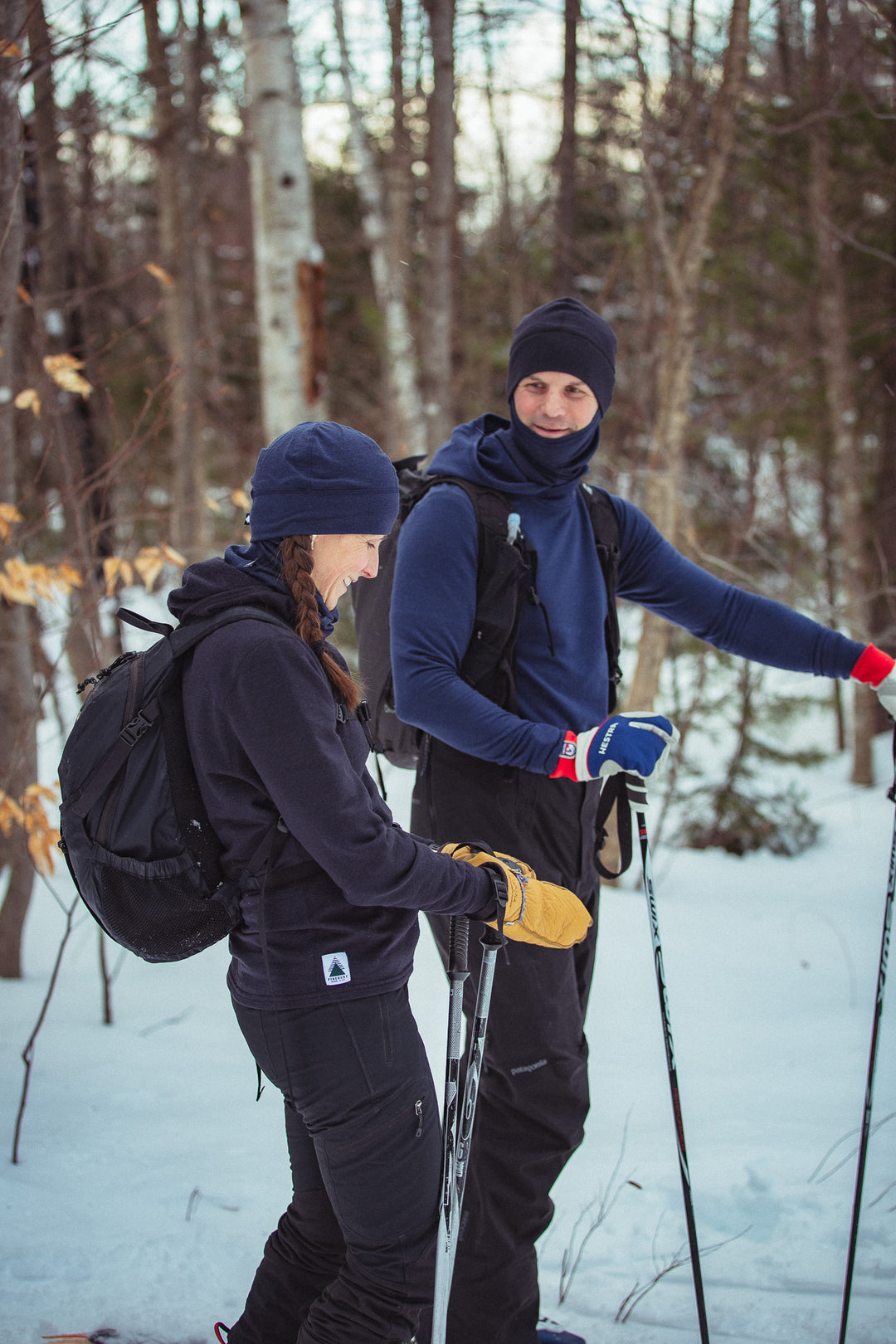 man and woman skiing with trees in the background.