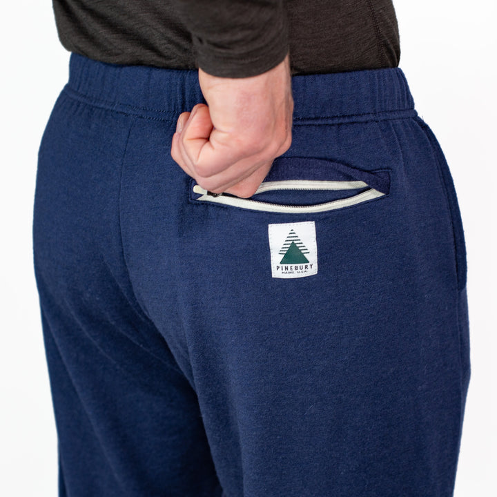 Navy blue sweatpants with a logo on the pocket against a white background