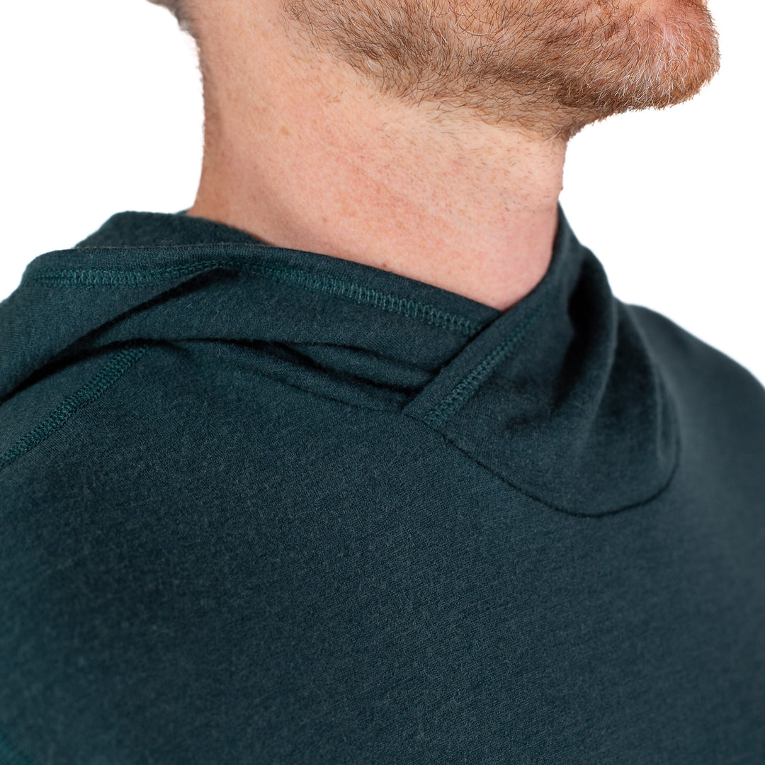 Close-up of a person wearing a dark green hoodie with a blurred background