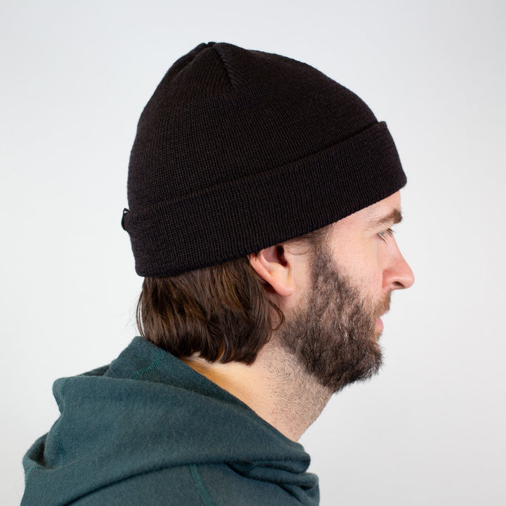 Person wearing a black beanie and green hoodie against a white background