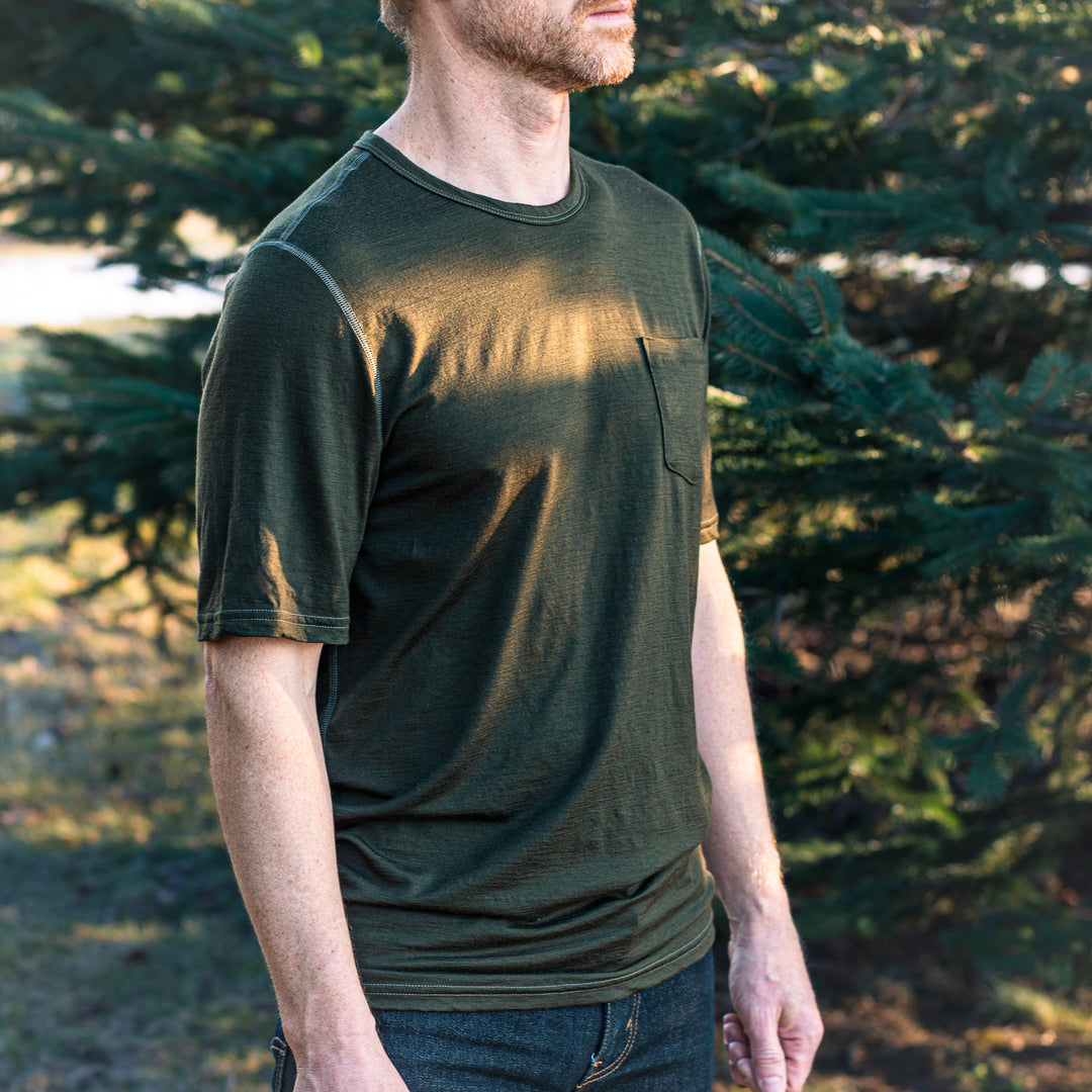 Man wearing a green t-shirt standing outdoors with trees in the background