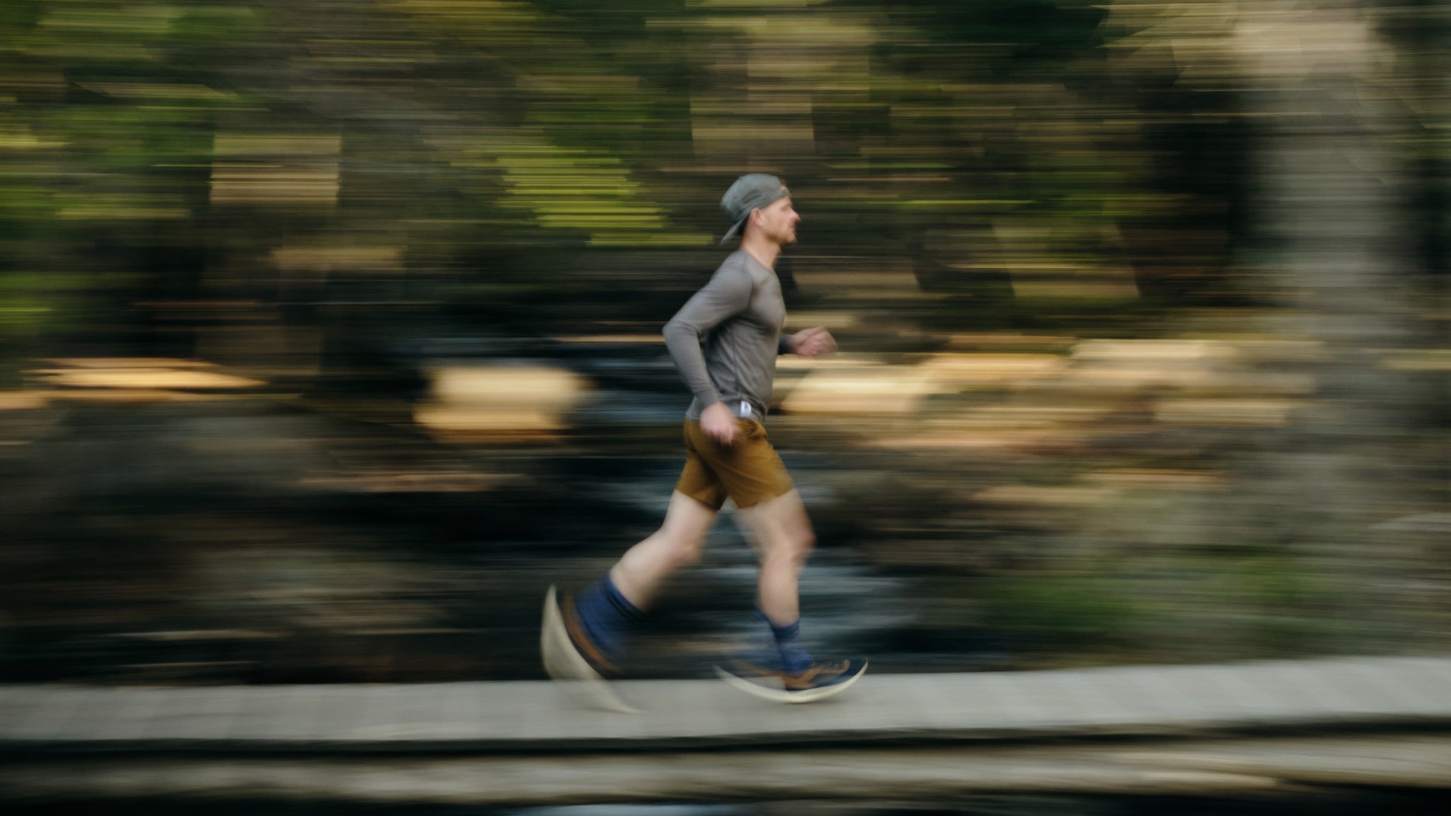 Pan shot of trail runner running on a wooden bridge in Acadia National Park in Maine, wearing a Pinebury Portland Long Sleeve Merino Wool Performance Tee in Grafton