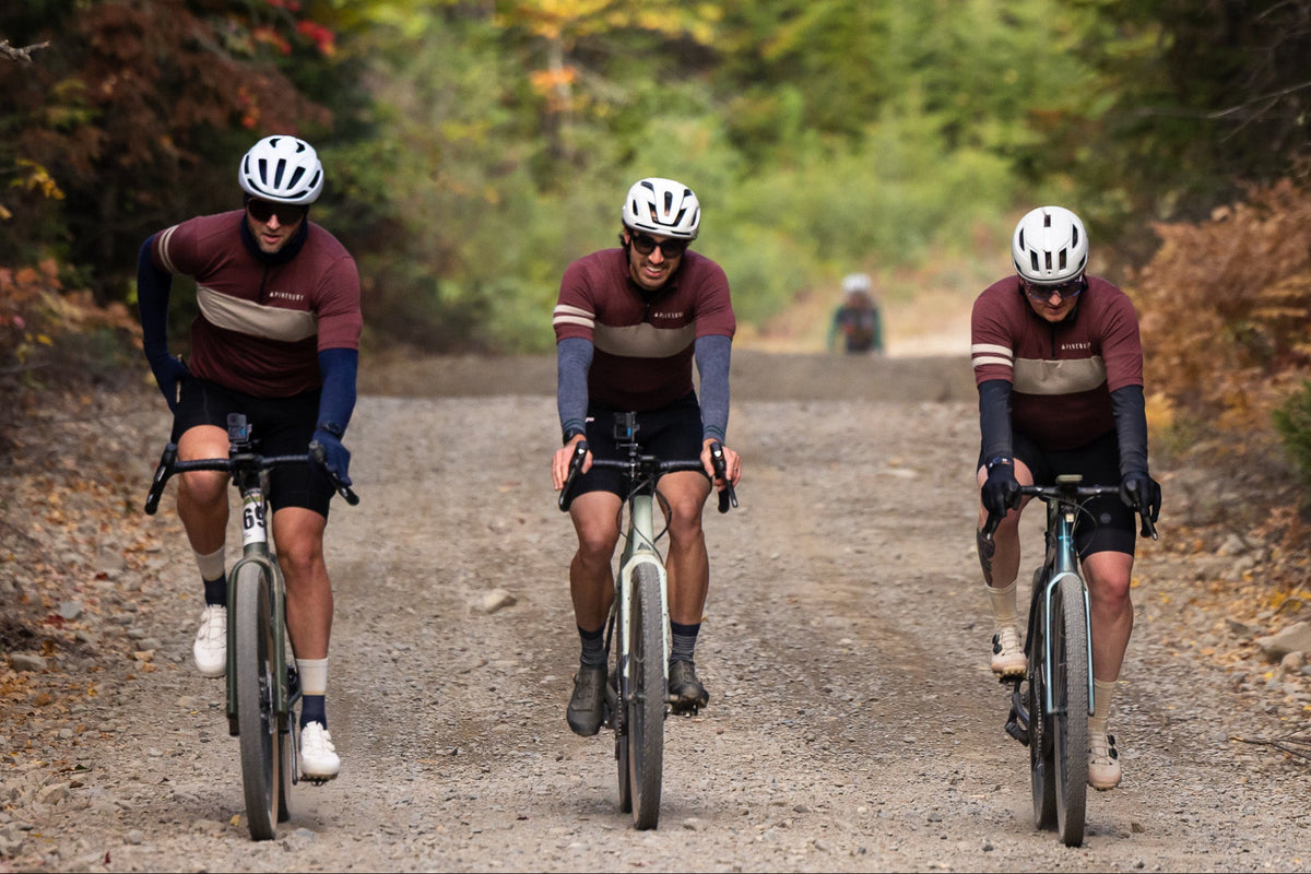 Three riders in Pinebury merino wool kit on a fall gravel road