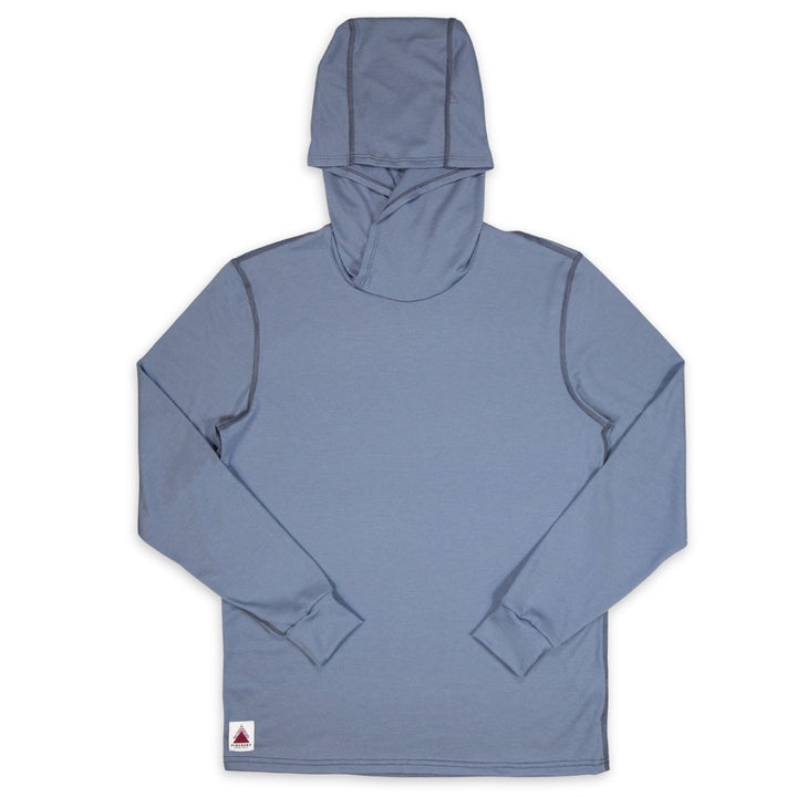 A dusty blue long-sleeve hooded shirt with a high collar, laid flat against a white background. It features a small white brand tag near the bottom left hem.