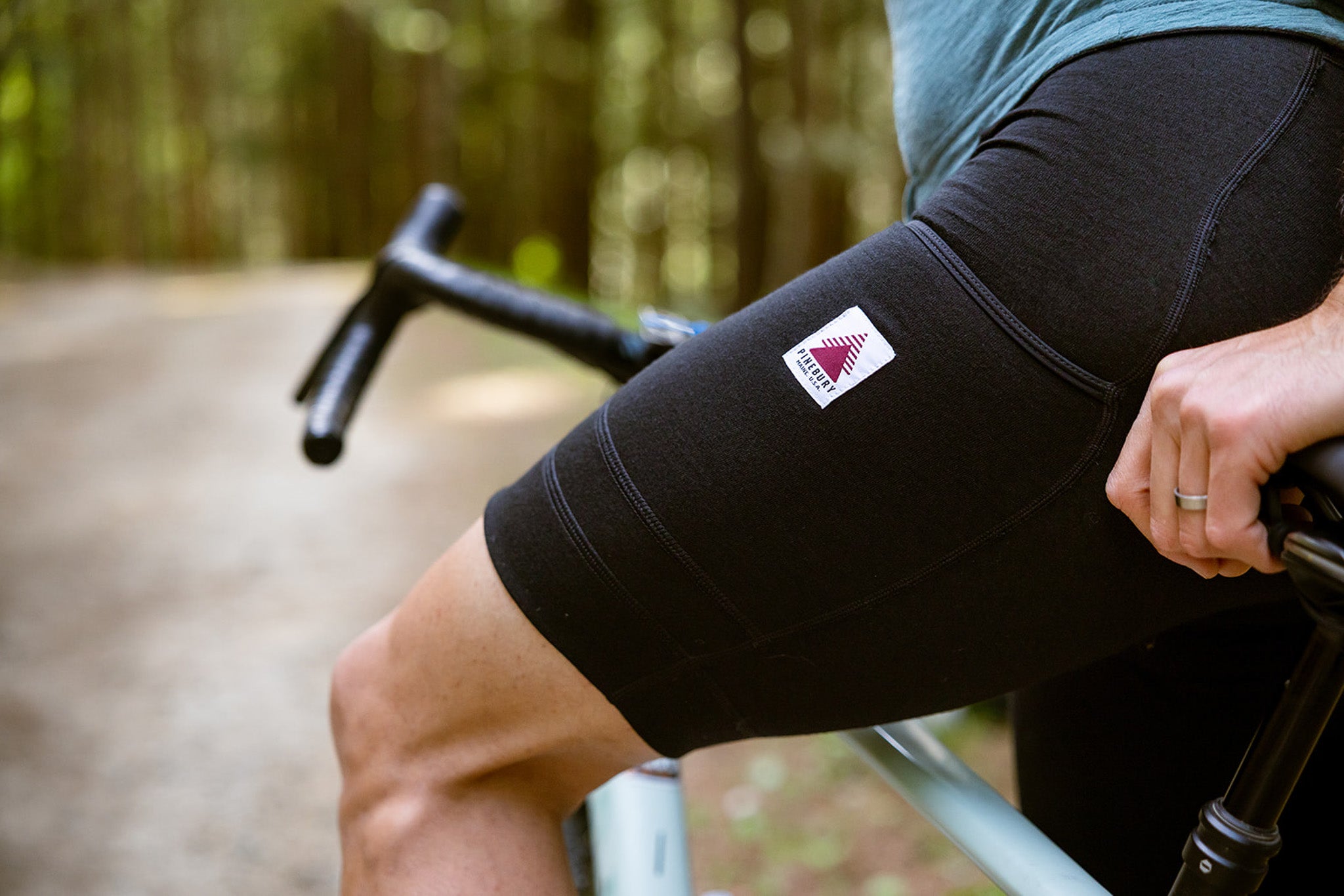 Person wearing black cycling shorts with a visible brand logo on a blurred outdoor background