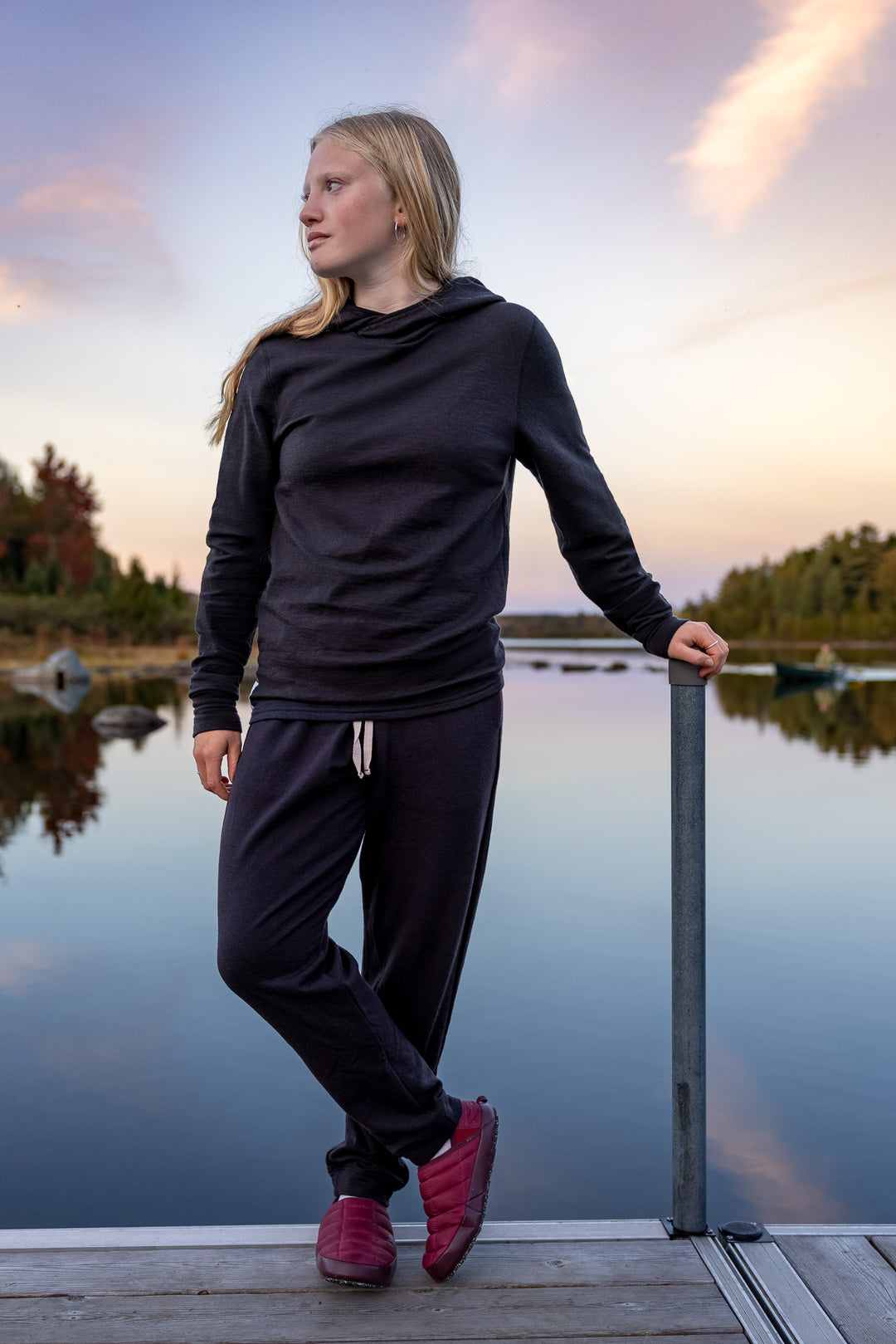 Woman in black outfit standing by a lake at sunset