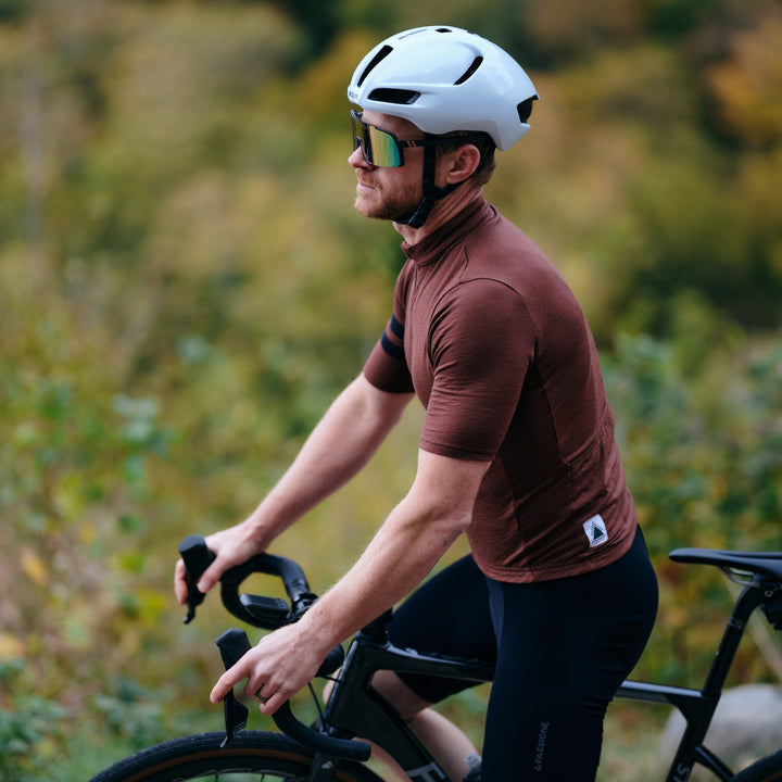 Pinebury Grafton Short Sleeve Merino Wool Cycling Jersey in Brick Red, Man in white helmet getting ready to ride